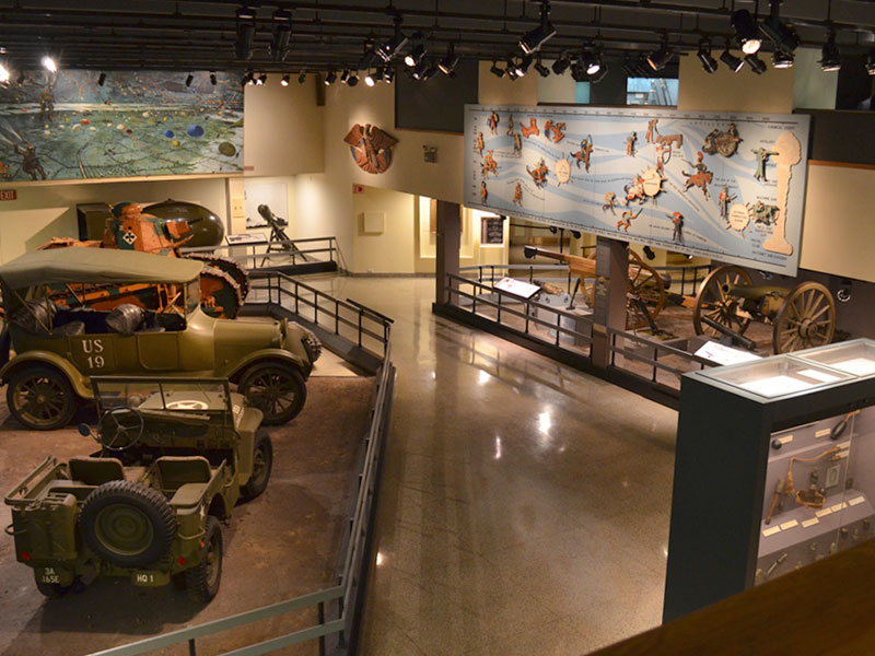 A room inside the West Point museum featuring automobiles on display.